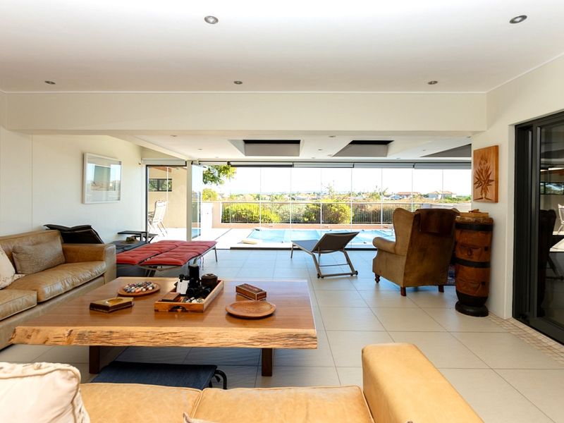 Spacious open-plan living area featuring large sliding glass doors that open onto a patio with a swimming pool and scenic views.
