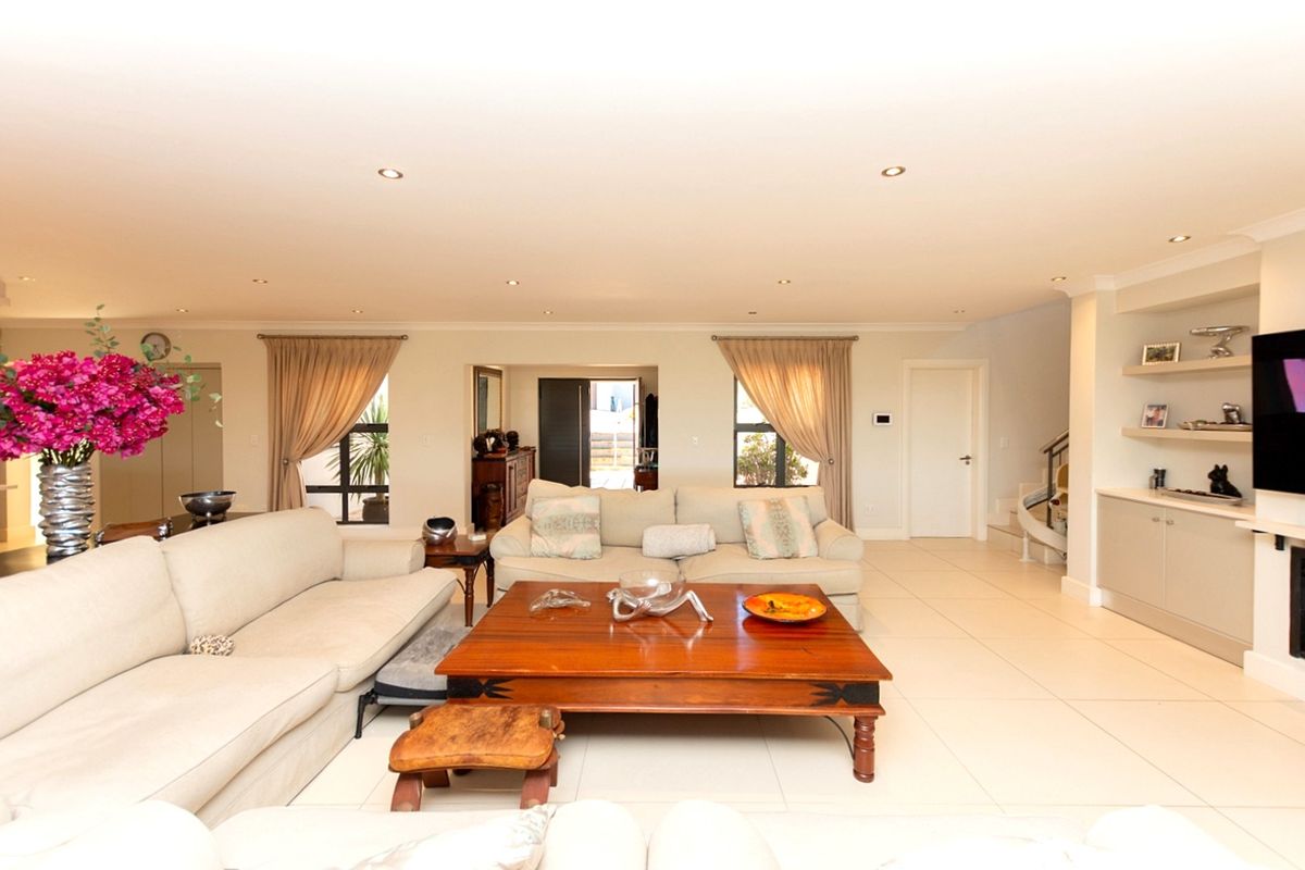 Spacious living room featuring neutral tiled flooring, recessed downlights, and built-in shelving units, creating a bright and well-maintained open living space.