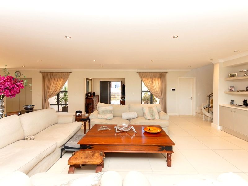 Spacious living room featuring neutral tiled flooring, recessed downlights, and built-in shelving units, creating a bright and well-maintained open living space.