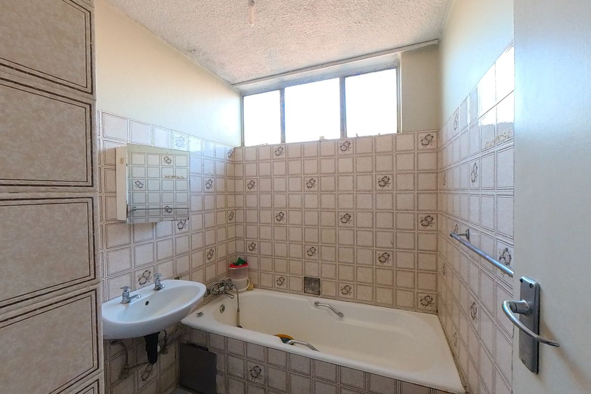 A dated bathroom featuring a standard bathtub, pedestal basin, and tiled walls, offering a blank canvas for a modern renovation.