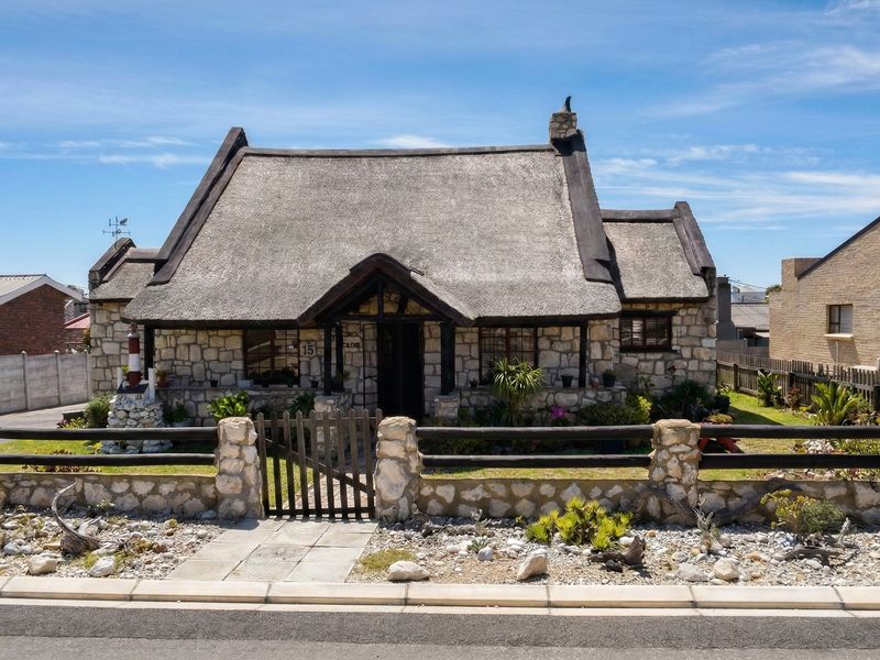 Charming cottage-style home featuring a traditional thatched roof, stone facade, and a well-maintained front garden with timber fencing.