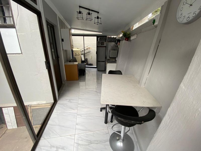 A narrow kitchen area featuring tiled flooring, built-in cabinetry, and sliding glass doors leading to an outdoor space.