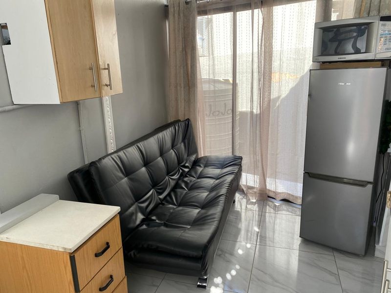 Compact open-plan living area featuring tiled flooring, built-in cabinetry, and a sliding glass door providing access to the exterior.