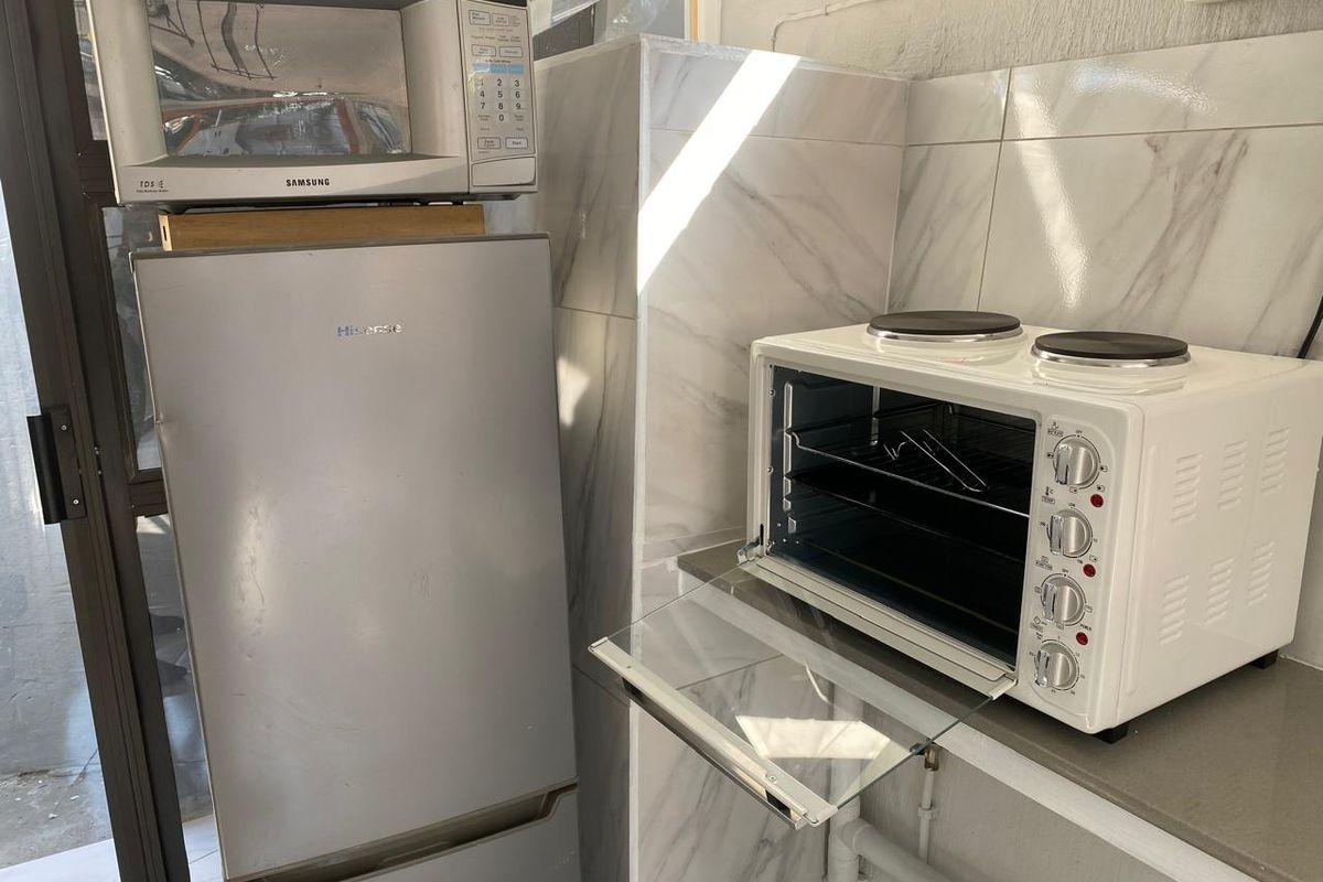 A compact kitchen area featuring marble-effect wall tiling and a functional countertop space with visible plumbing.