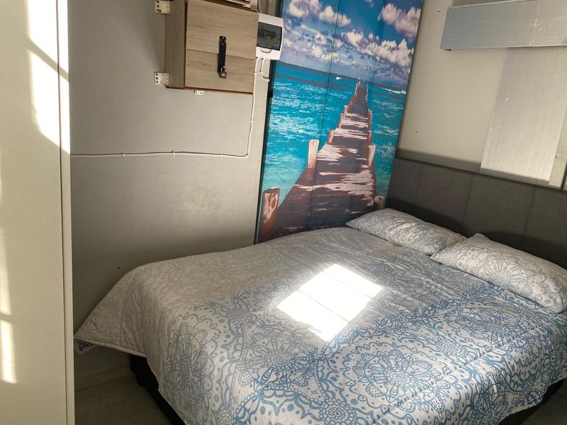 A bedroom featuring an exposed electrical distribution board and wall-mounted wiring, requiring cosmetic updates to improve the overall finish and aesthetic appeal.