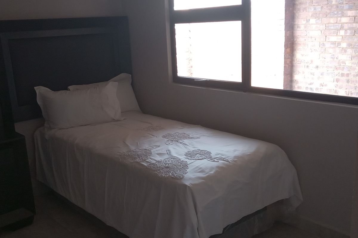 A compact bedroom featuring built-in cabinetry and a large window providing natural light.