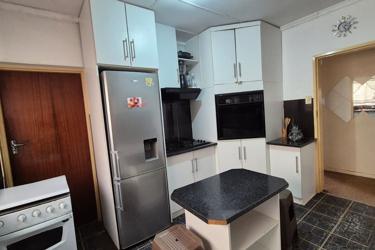 A functional kitchen featuring white built-in cabinetry, dark laminate countertops, a built-in oven, and an extractor fan with tiled flooring.