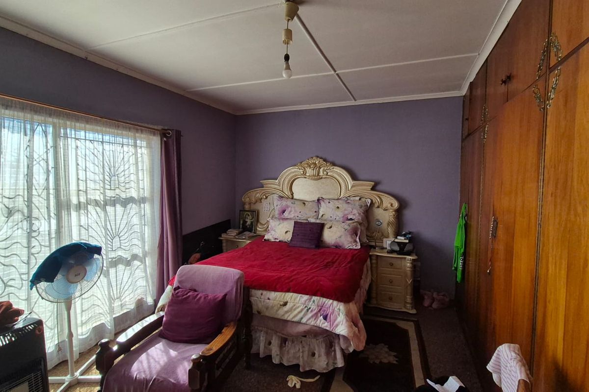 A bedroom featuring built-in wooden cupboards, sliding glass doors with security gates, and carpeted flooring.