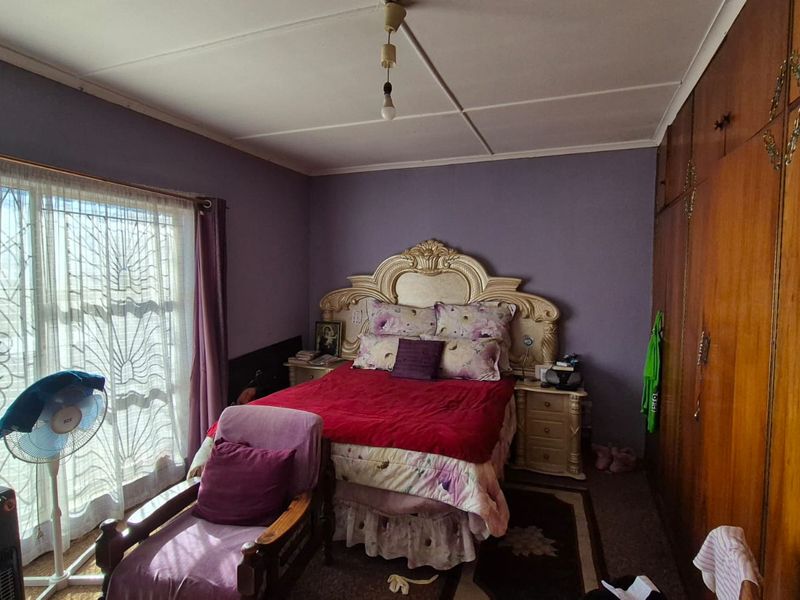 A bedroom featuring built-in wooden cupboards, sliding glass doors with security gates, and carpeted flooring.