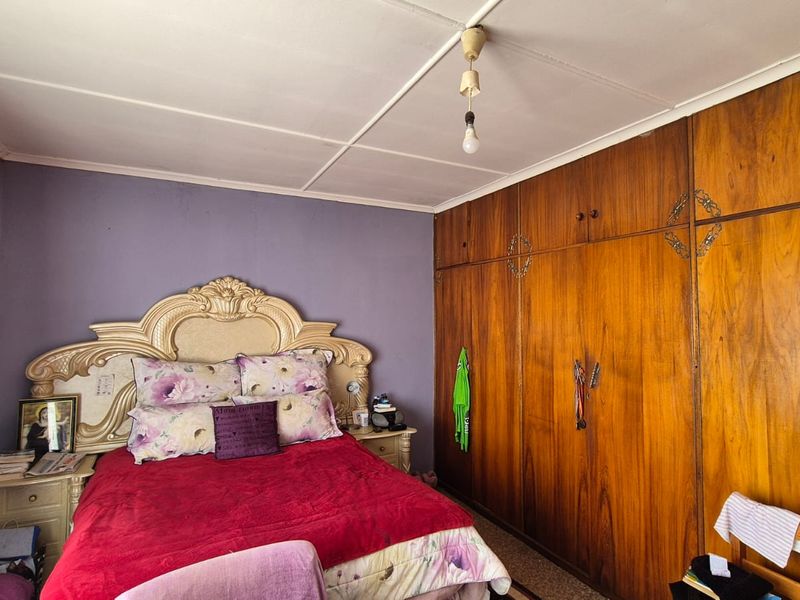 A bedroom featuring extensive built-in wooden cabinetry and a tiled ceiling, offering significant storage space with potential for cosmetic modernization.