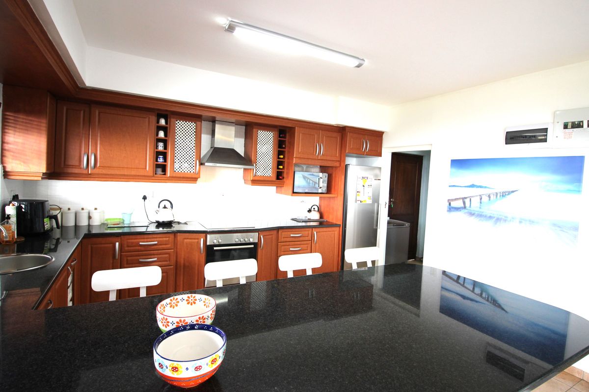 A functional kitchen featuring dark granite countertops, wooden cabinetry, and integrated appliances, offering a practical workspace with ample storage.