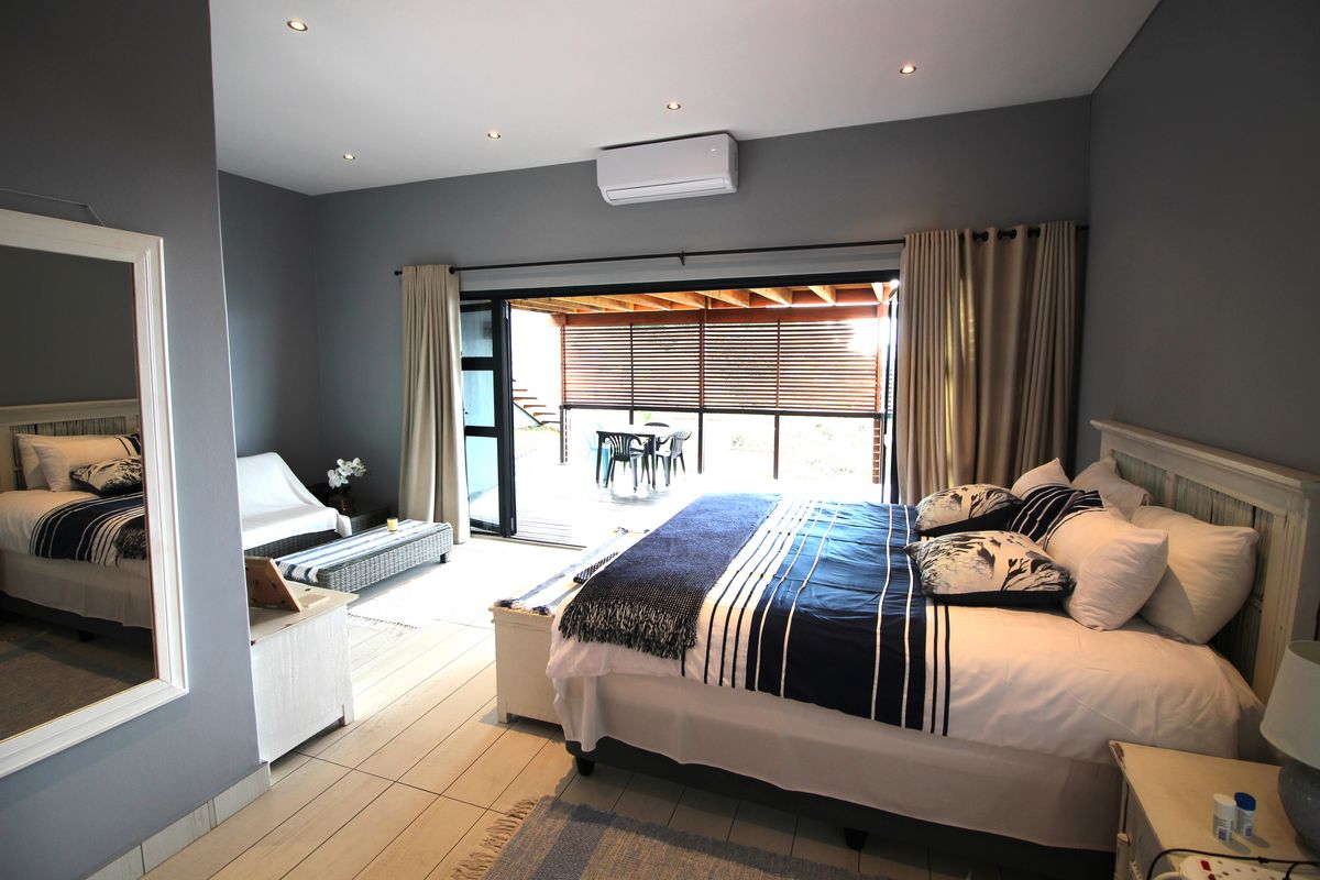 Spacious bedroom featuring tiled flooring, recessed lighting, split-system air conditioning, and large sliding glass doors opening onto a covered patio area.