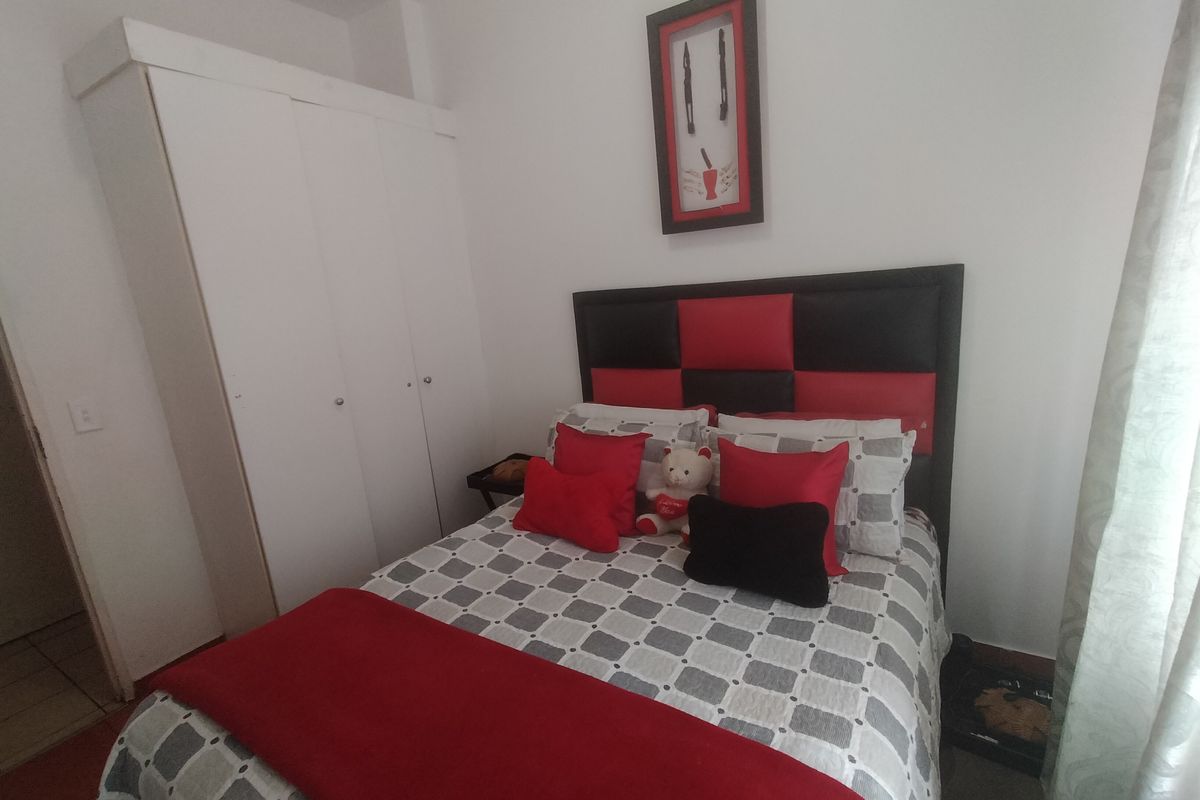 A functional bedroom featuring a built-in wardrobe and neutral wall finishes, providing a practical sleeping space.
