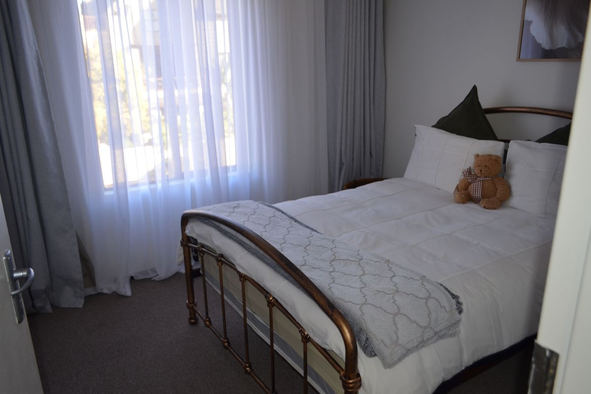 A cozy bedroom featuring neutral carpet flooring and floor-to-ceiling window treatments, providing a comfortable and well-maintained living space.