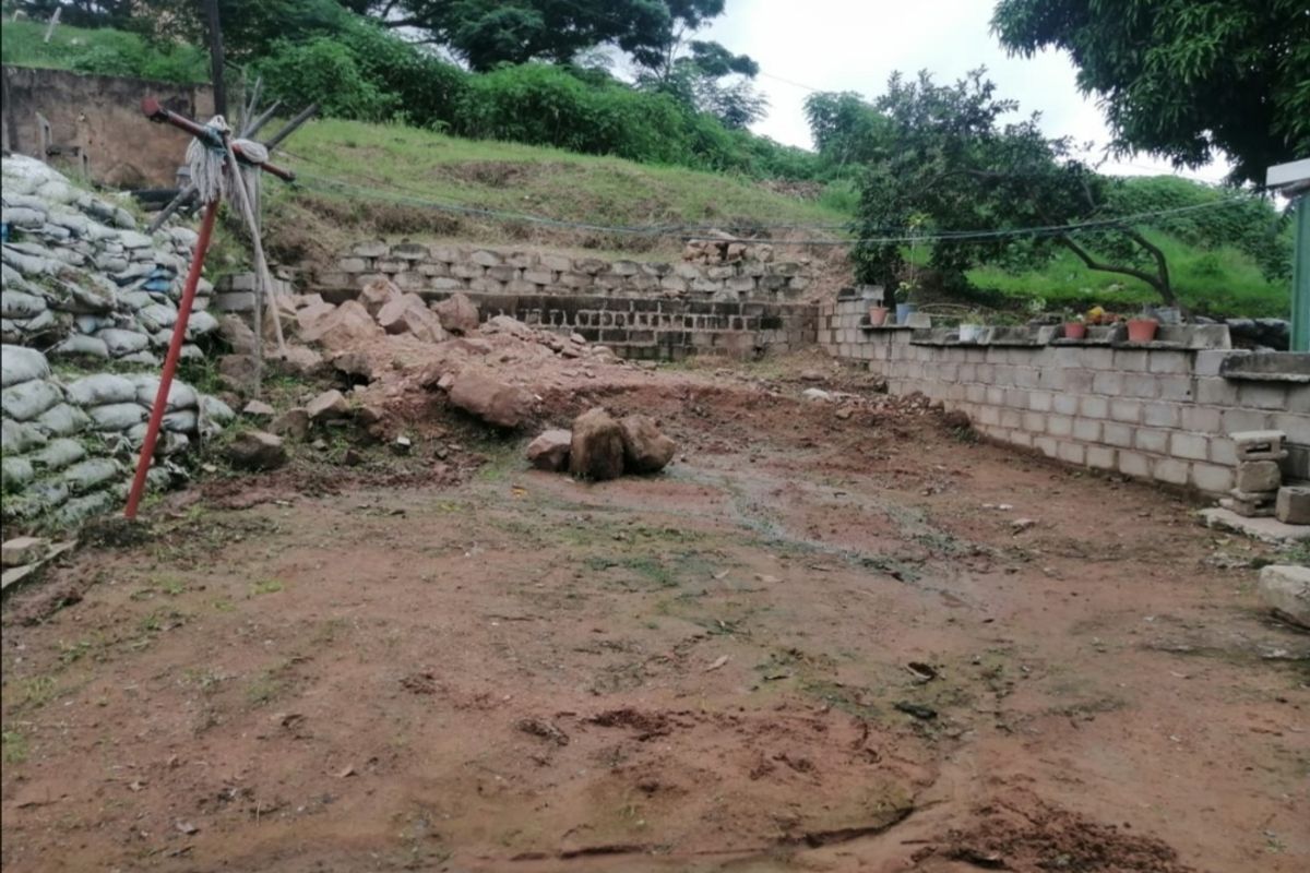 An undeveloped rear garden area featuring unfinished concrete block retaining walls, exposed earth, and significant landscaping work required.