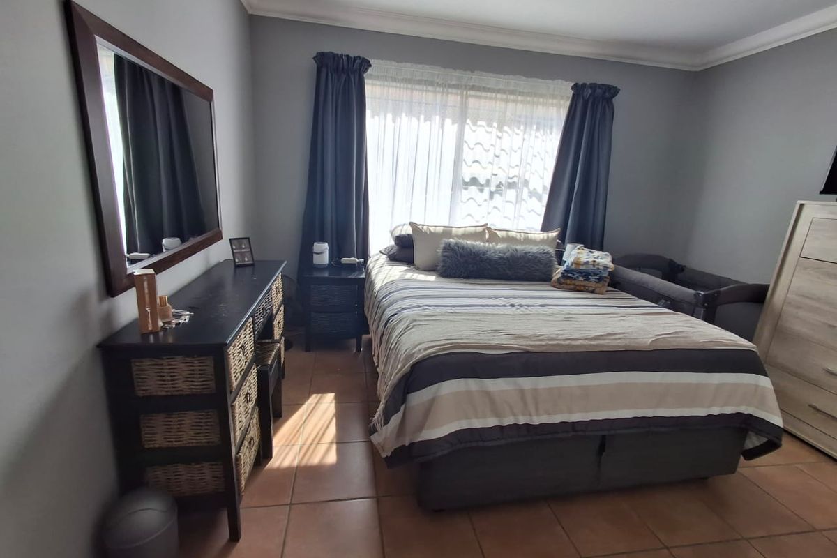 A bedroom featuring tiled flooring, neutral wall paint, and a sliding window with curtain tracks.