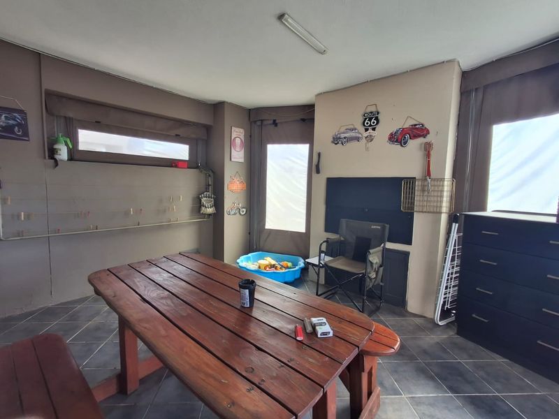 A covered patio area featuring tiled flooring and a wall-mounted drying rack, providing a functional outdoor space for relaxation or utility use.