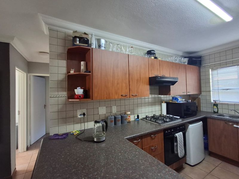 A functional kitchen featuring laminate cabinetry, gas hob, built-in oven, and tiled finishes, offering a practical layout with potential for modern cosmetic updates.