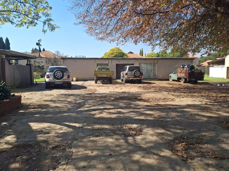 Front view of the property featuring a large concrete driveway and a single-story building structure with a garage and sliding door access.