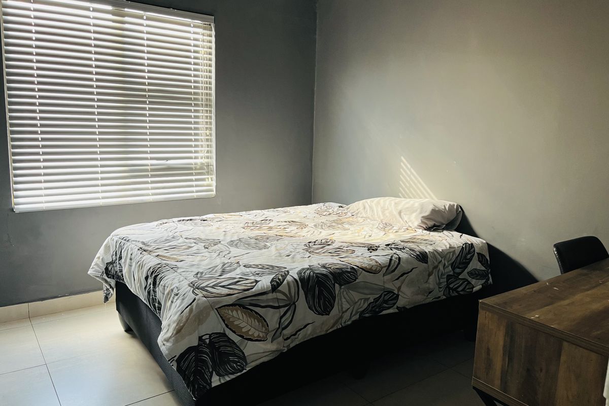 A bedroom featuring tiled flooring and venetian blinds, providing a neutral space ready for personalization.