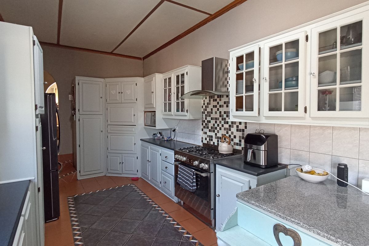 A functional kitchen featuring built-in cabinetry, granite countertops, a gas stove with extractor fan, and a tiled backsplash.