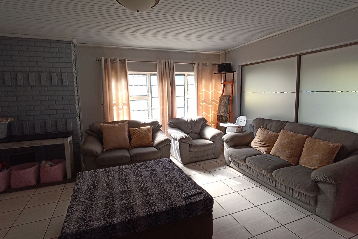 A spacious living room featuring tiled flooring, a painted brick fireplace, and frosted glass sliding doors, offering a comfortable and functional family space.