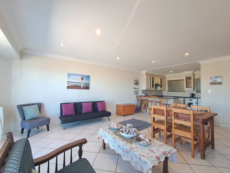 Spacious open-plan living and dining area featuring tiled floors, recessed lighting, and a functional kitchen with built-in cabinetry and integrated appliances.