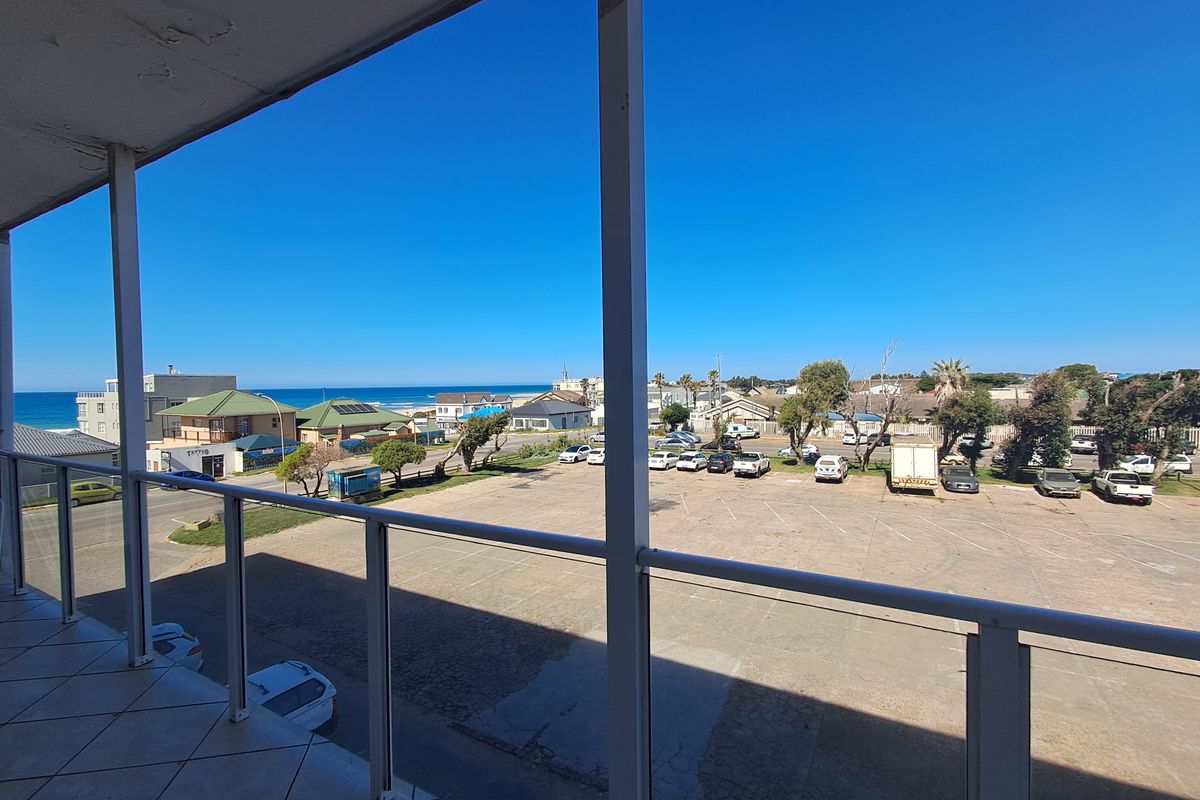 A balcony featuring tiled flooring and a metal balustrade, offering an elevated view of the surrounding area and coastline.