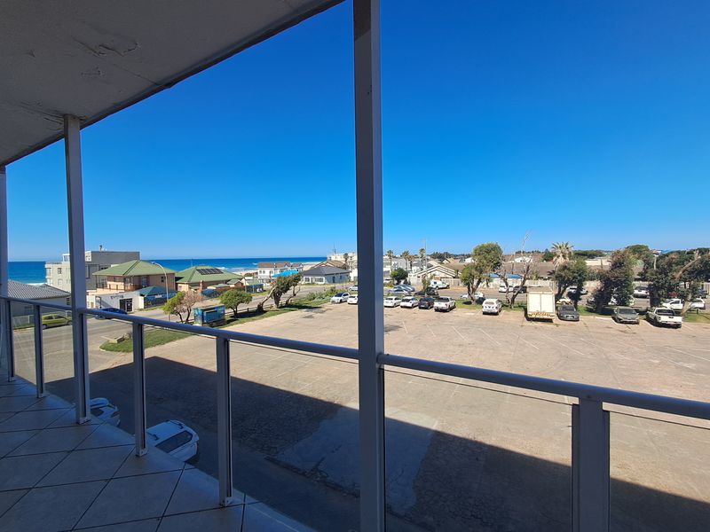 A balcony featuring tiled flooring and a metal balustrade, offering an elevated view of the surrounding area and coastline.