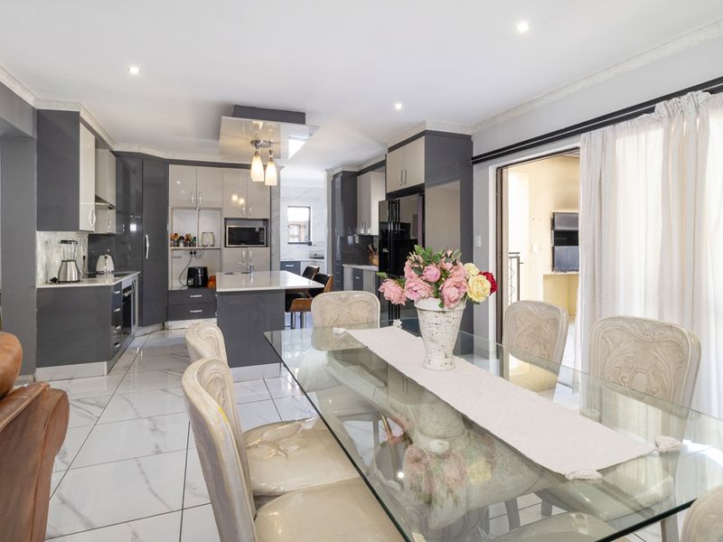 Modern open-plan kitchen and dining area featuring high-gloss cabinetry, a central island, and polished marble-look floor tiles.