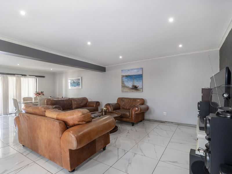 Spacious open-plan living area featuring polished marble-look floor tiles, recessed downlighting, and direct access to an outdoor patio through sliding glass doors.