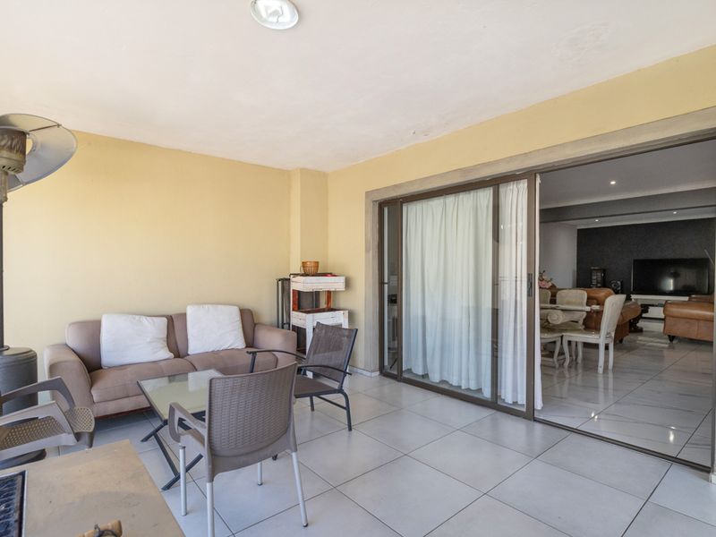 Covered patio area featuring tiled flooring and large sliding glass doors providing seamless access to the interior living space.