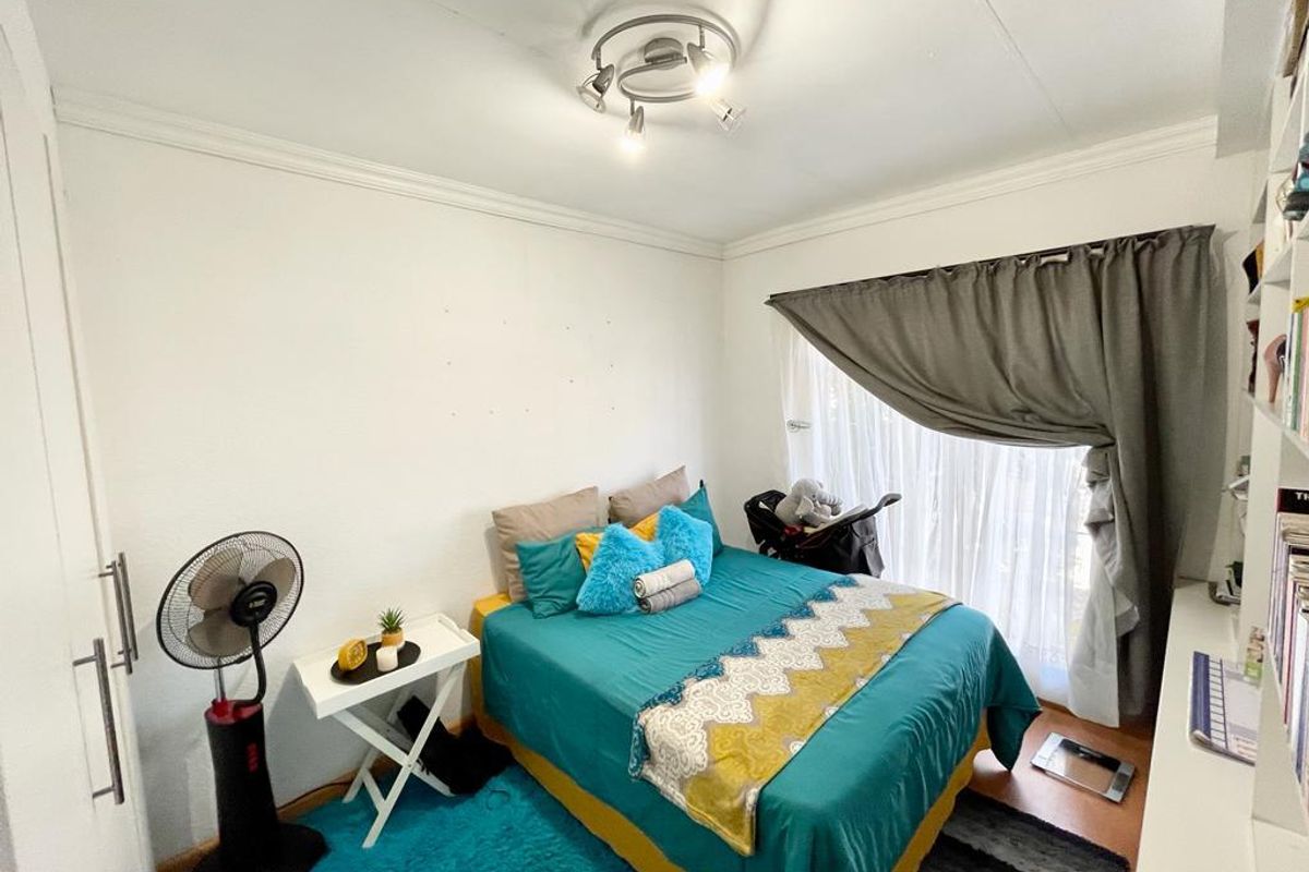 A functional bedroom featuring built-in cabinetry, crown molding, and a large window with curtain tracks, providing a comfortable and well-lit living space.