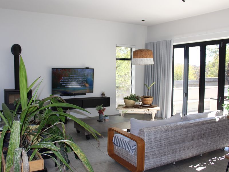 Modern living room featuring tiled floors, a freestanding fireplace, and large black aluminium bifold doors opening to an outdoor area.