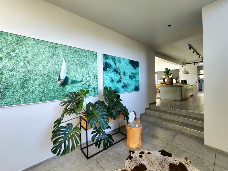 A modern, well-lit entrance hall featuring large-format floor tiles and concrete steps leading to an open-plan living and kitchen area.