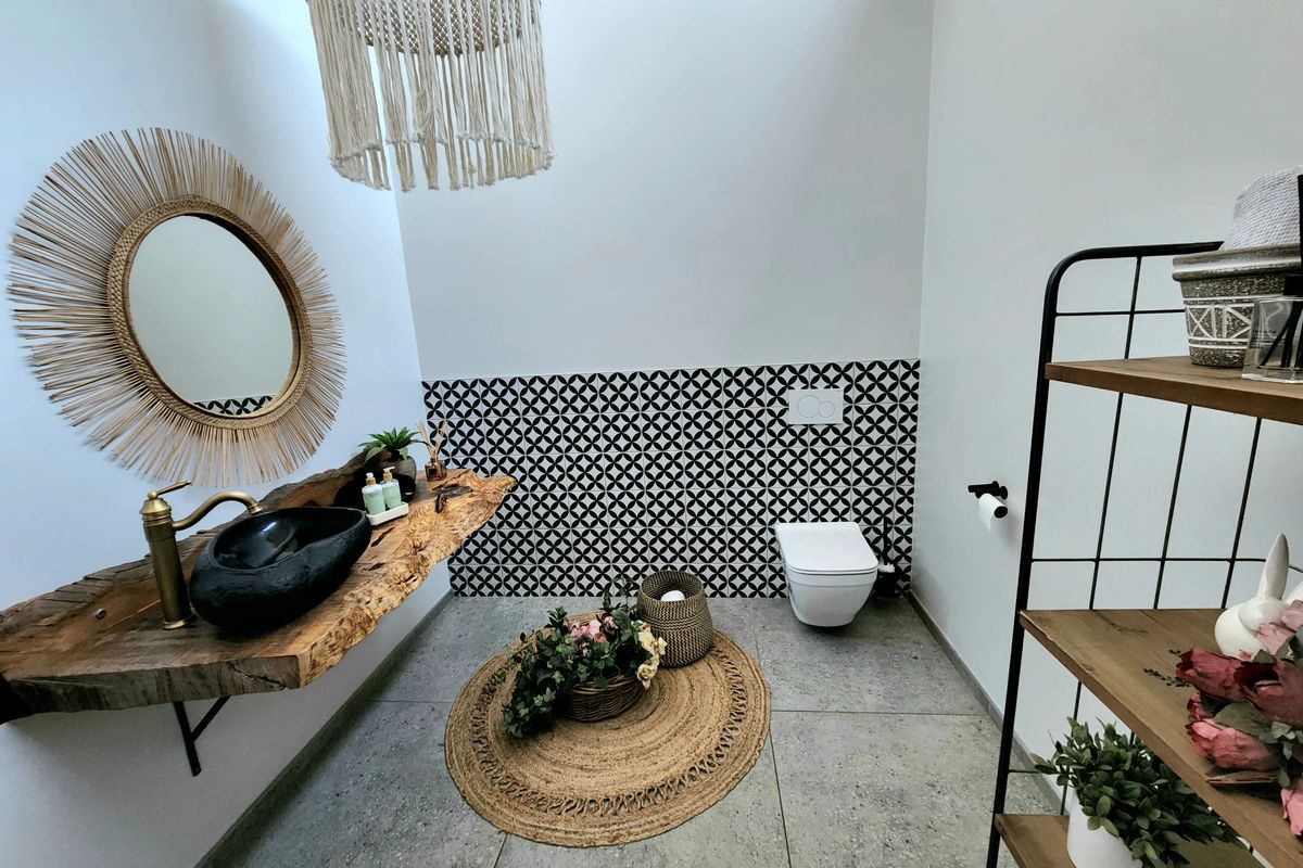 Modern bathroom featuring a unique live edge wood vanity with a black vessel sink, wall-mounted toilet, and striking patterned accent tiling.