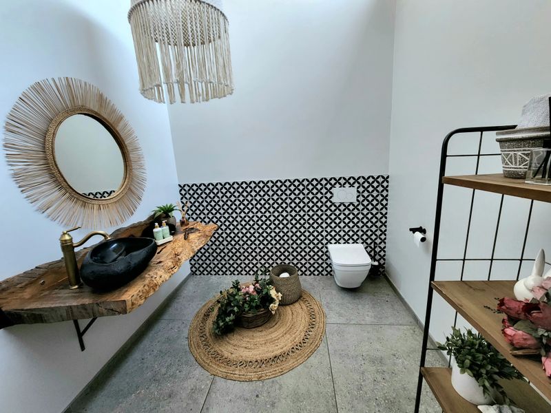Modern bathroom featuring a unique live edge wood vanity with a black vessel sink, wall-mounted toilet, and striking patterned accent tiling.