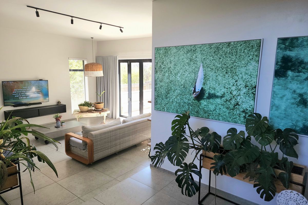 A bright and modern living room featuring large format floor tiles, track lighting, and bi-fold doors leading to an outdoor area.