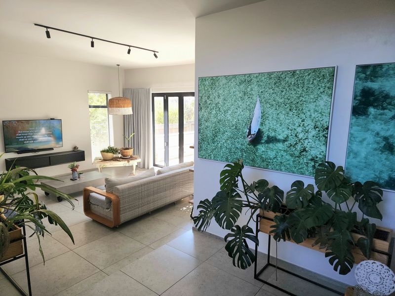 A bright and modern living room featuring large format floor tiles, track lighting, and bi-fold doors leading to an outdoor area.