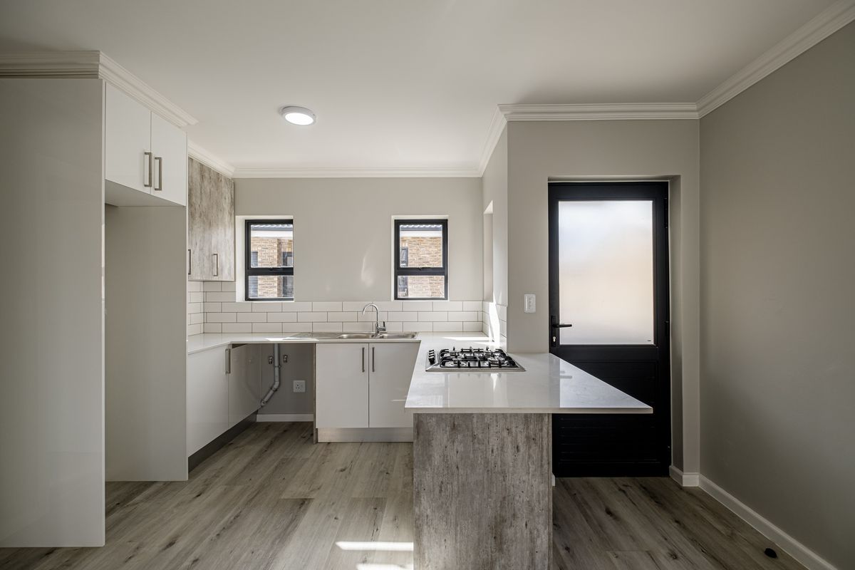 Modern kitchen featuring white cabinetry, stone countertops, a built-in gas hob, subway tile backsplash, and wood-look flooring with direct exterior access.