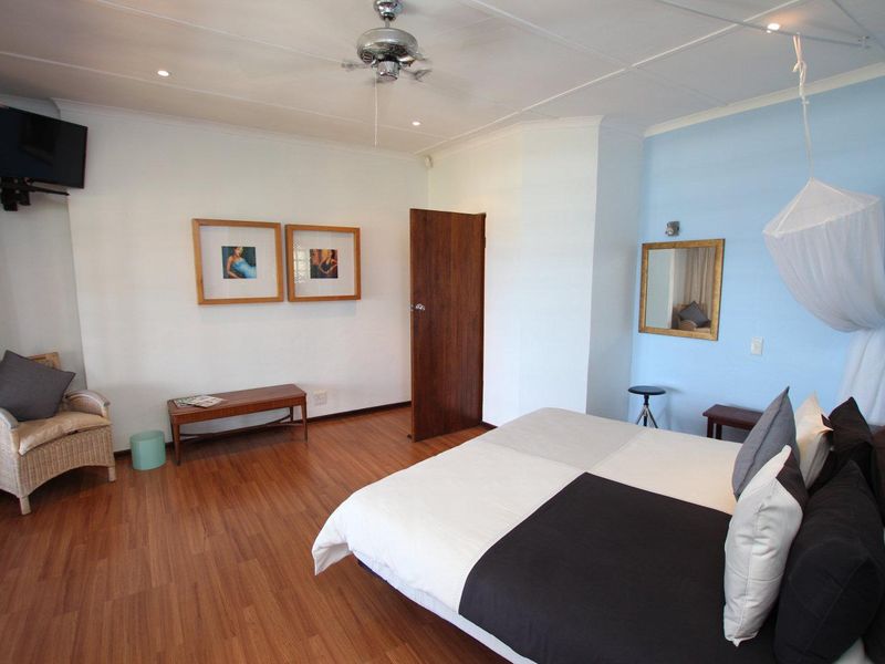 A spacious bedroom featuring laminate flooring, a ceiling fan, and recessed lighting, offering a comfortable and functional living space.
