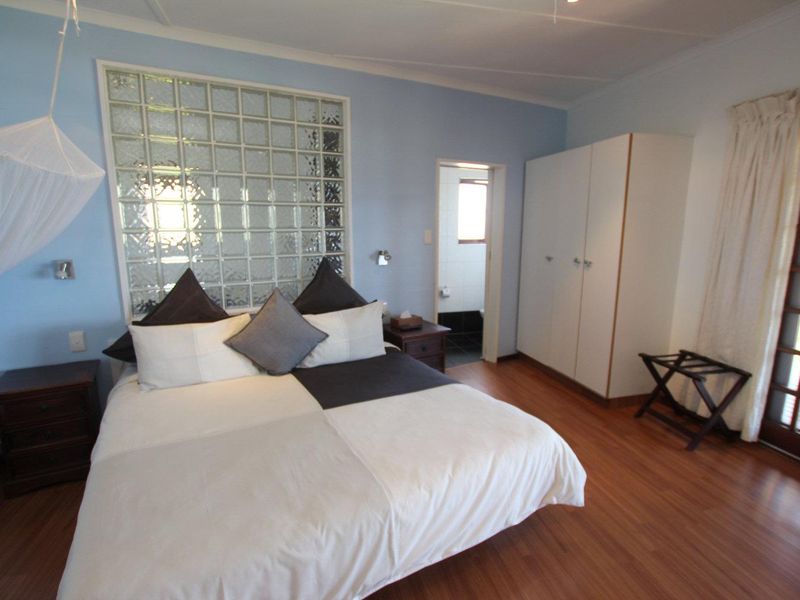 A bedroom featuring laminate flooring, a glass block feature wall, built-in wardrobe, and direct access to an outdoor area through a glass panel door.