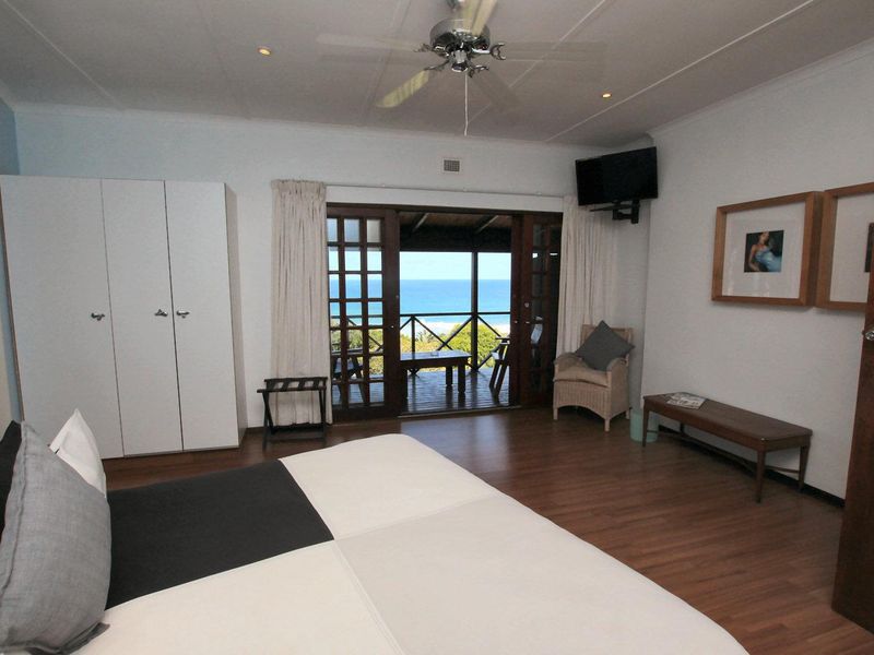 Spacious bedroom featuring laminate flooring, built-in wardrobes, and direct access to a private balcony with scenic ocean views.