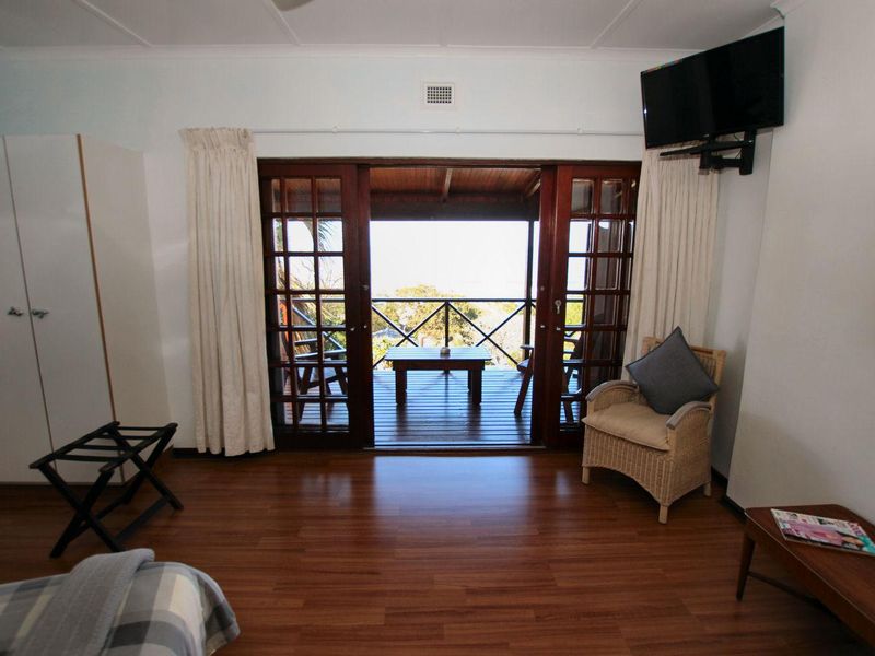 A well-maintained bedroom featuring laminate flooring, built-in storage, and wooden sliding doors that open onto a private balcony with scenic views.