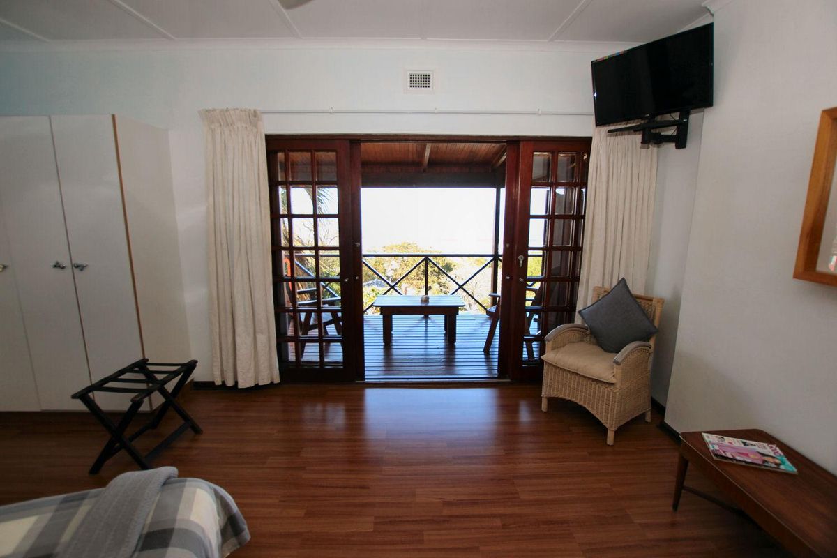 A well-maintained bedroom featuring laminate flooring, built-in storage, and wooden sliding doors that open onto a private balcony with scenic views.