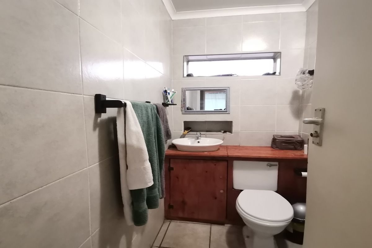 A functional bathroom featuring tiled walls and floors, a vanity cabinet with a countertop basin, and a standard toilet.