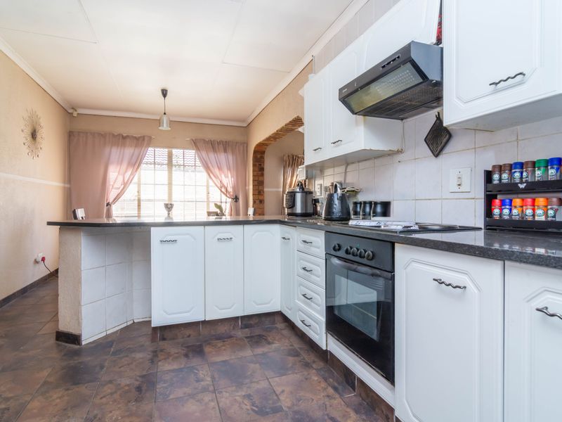 Functional kitchen featuring white cabinetry, granite countertops, built-in oven, extractor fan, and a breakfast bar area with tiled flooring.