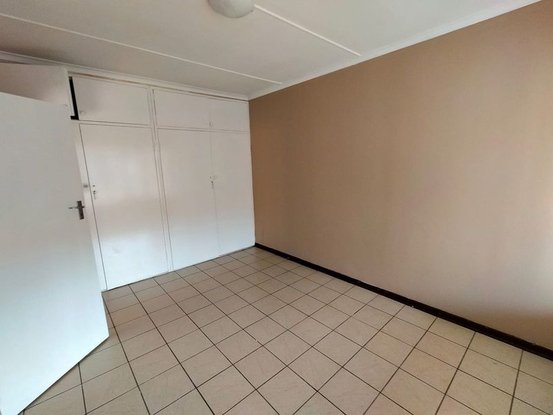 An empty bedroom featuring tiled flooring and built-in cupboards, providing a blank canvas for personalization.