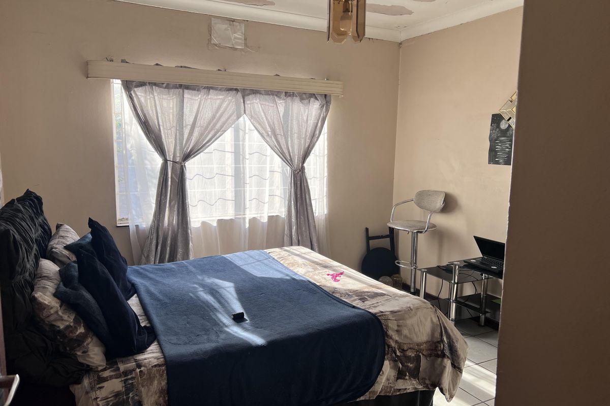 A bedroom featuring tiled flooring and window security bars, currently requiring ceiling repairs and cosmetic updates to improve the overall condition.