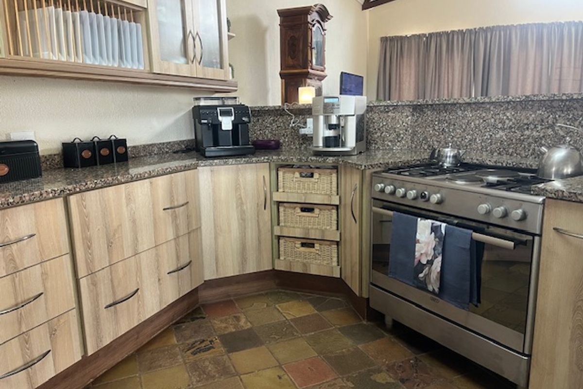 A functional kitchen featuring wood-finish cabinetry, granite countertops, stone tile flooring, and a stainless steel gas stove.